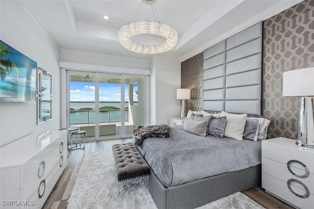 bedroom with recessed lighting, an accent wall, wood finished floors, access to exterior, and a raised ceiling