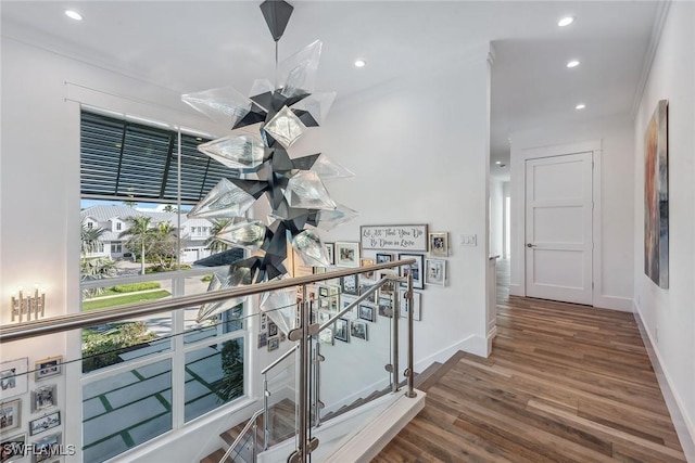 hall featuring recessed lighting, ornamental molding, an upstairs landing, wood finished floors, and baseboards