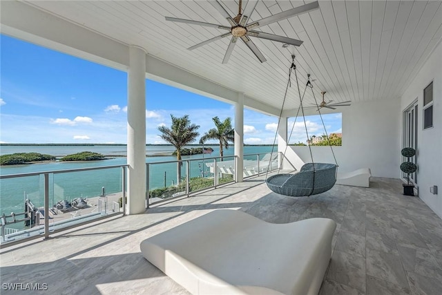 view of patio / terrace featuring a water view, a balcony, and a ceiling fan