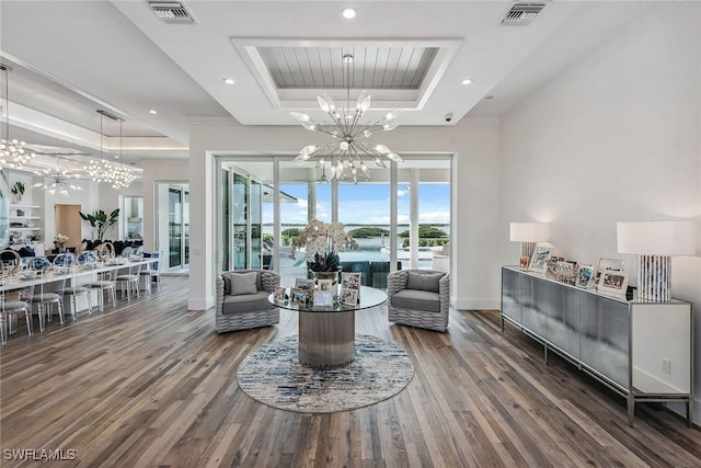 living area with visible vents, a tray ceiling, a notable chandelier, and wood finished floors