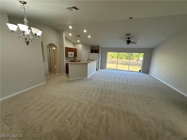 unfurnished living room with vaulted ceiling, light carpet, and ceiling fan with notable chandelier