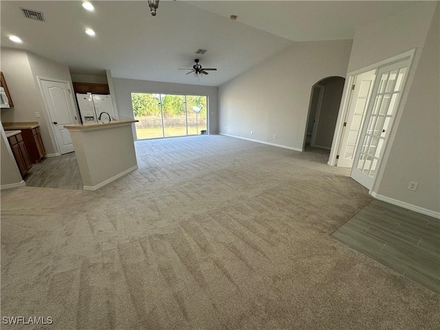 unfurnished living room with vaulted ceiling, light colored carpet, and ceiling fan