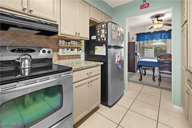 kitchen with extractor fan, tasteful backsplash, light tile patterned floors, appliances with stainless steel finishes, and cream cabinetry