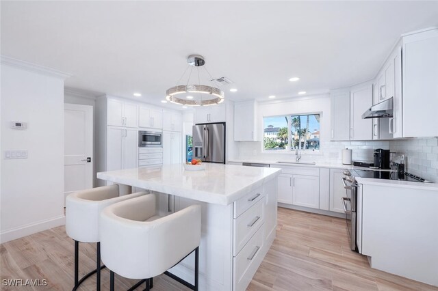 418 Germain Ave, Naples, FL 34108 - kitchen with appliances with stainless steel finishes, a sink, decorative backsplash, white cabinetry, and a kitchen bar