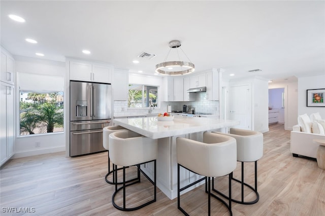 418 Germain Ave, Naples, FL 34108 - kitchen featuring stainless steel fridge, light countertops, white cabinetry, a kitchen bar, and recessed lighting