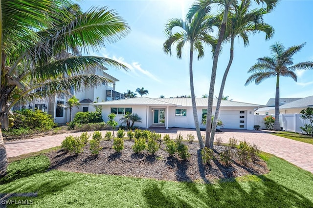 418 Germain Ave, Naples, FL 34108 - view of front facade with decorative driveway, an attached garage, stucco siding, and metal roof