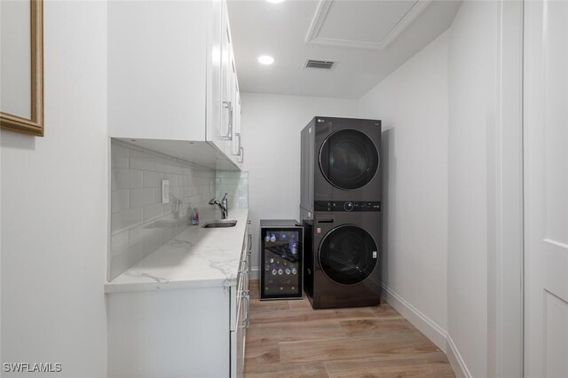 418 Germain Ave, Naples, FL 34108 - washroom with stacked washer and clothes dryer, wine cooler, cabinet space, light wood-style floors, and recessed lighting