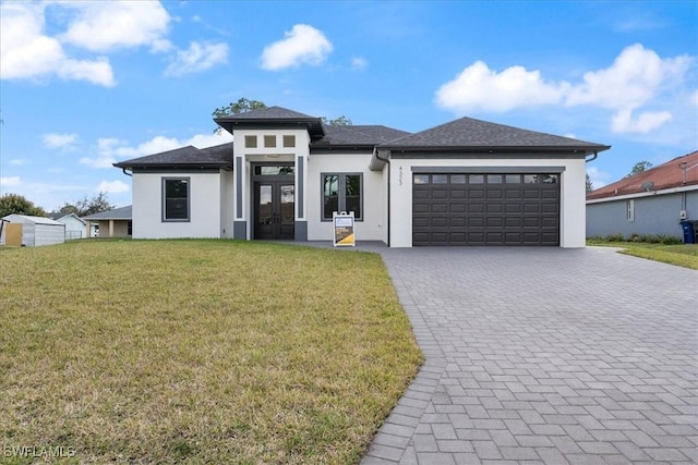 prairie-style house with a garage, french doors, decorative driveway, stucco siding, and a front lawn