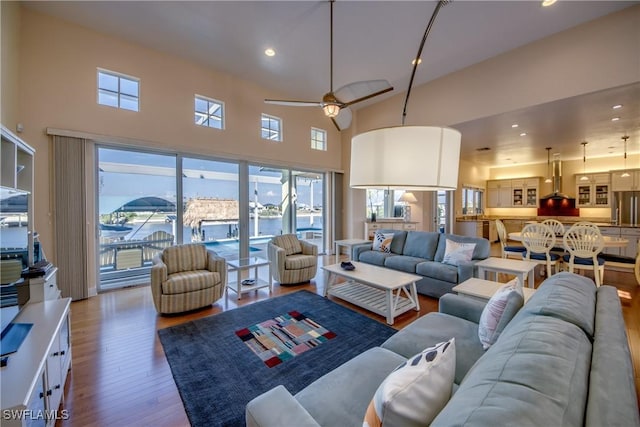 living room featuring hardwood / wood-style flooring, a towering ceiling, and ceiling fan