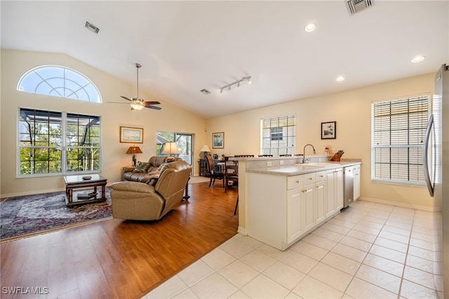 12206 Siesta Dr, Fort Myers Beach, FL 33931 - kitchen with vaulted ceiling, stainless steel appliances, light countertops, white cabinetry, and light wood-style flooring