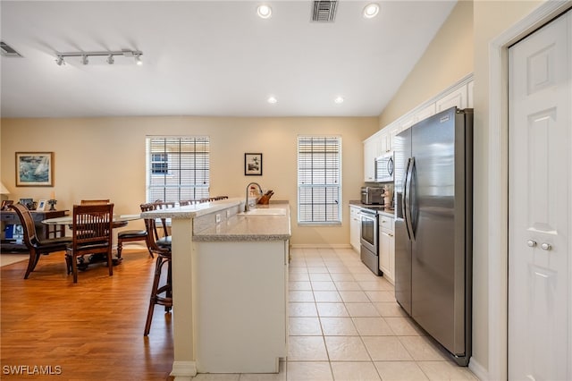 12206 Siesta Dr, Fort Myers Beach, FL 33931 - kitchen with stainless steel appliances, a kitchen bar, white cabinetry, recessed lighting, and track lighting