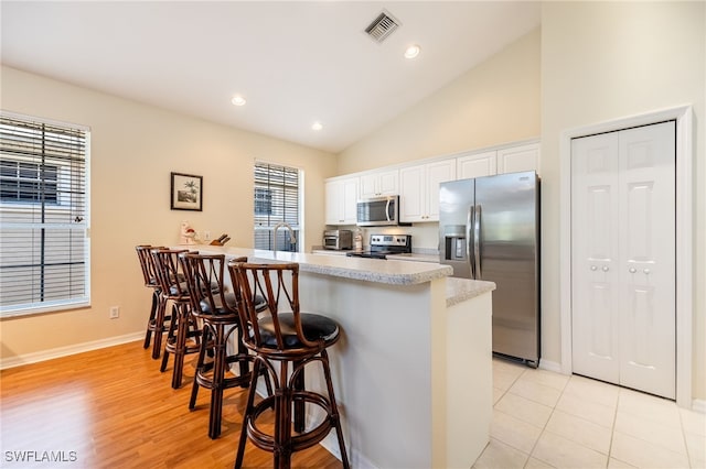 12206 Siesta Dr, Fort Myers Beach, FL 33931 - kitchen with stainless steel appliances, a kitchen breakfast bar, white cabinetry, light countertops, and a peninsula