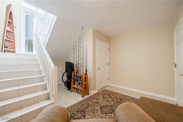 12206 Siesta Dr, Fort Myers Beach, FL 33931 - foyer entrance featuring tile patterned floors, a textured ceiling, and stairway