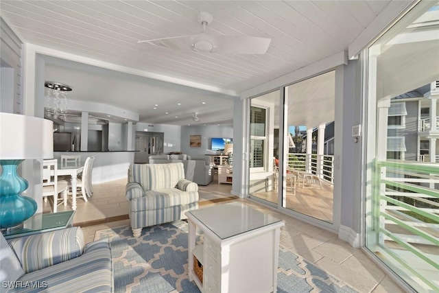 living area featuring a ceiling fan and a wall of windows