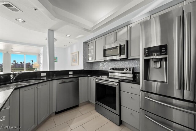 kitchen with tasteful backsplash, gray cabinets, visible vents, appliances with stainless steel finishes, and a sink