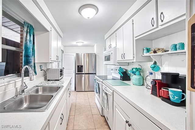 kitchen with backsplash, light tile patterned floors, a sink, and white appliances