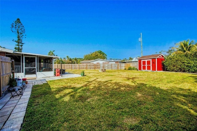 view of yard featuring a patio area, an outbuilding, a fenced backyard, a sunroom, and a storage unit