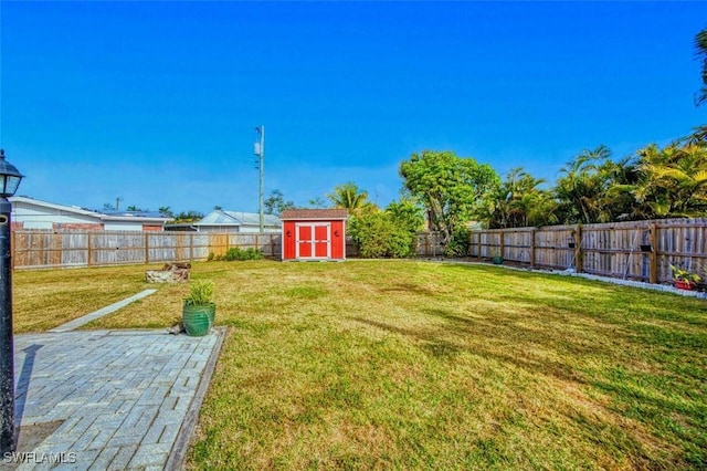 view of yard with a fenced backyard, an outbuilding, and a storage shed
