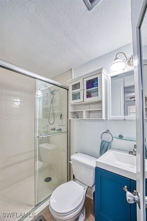 full bathroom with a stall shower, toilet, vanity, a textured ceiling, and visible vents