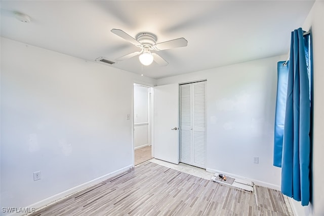 unfurnished bedroom with a closet, baseboards, light wood-style floors, and visible vents