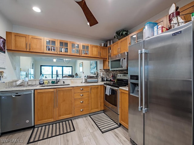 kitchen featuring a sink, stainless steel appliances, light countertops, and glass insert cabinets