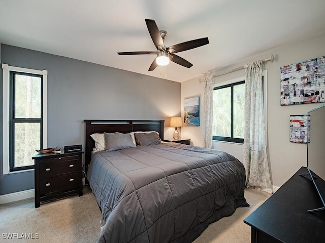 bedroom with light carpet, multiple windows, and baseboards