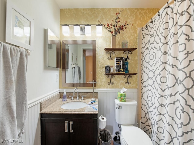 full bath featuring a wainscoted wall, toilet, and wallpapered walls