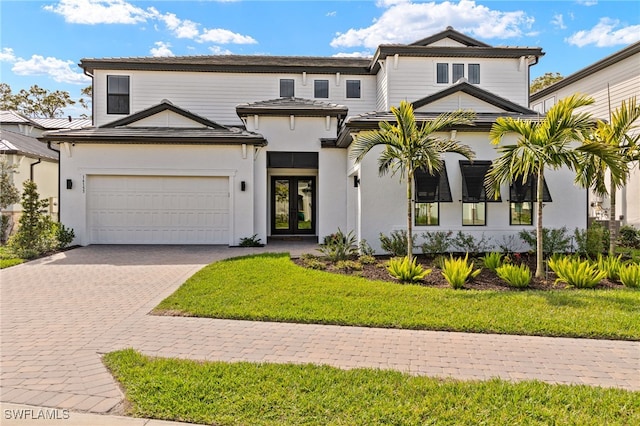 view of front of home with french doors, decorative driveway, and a front yard