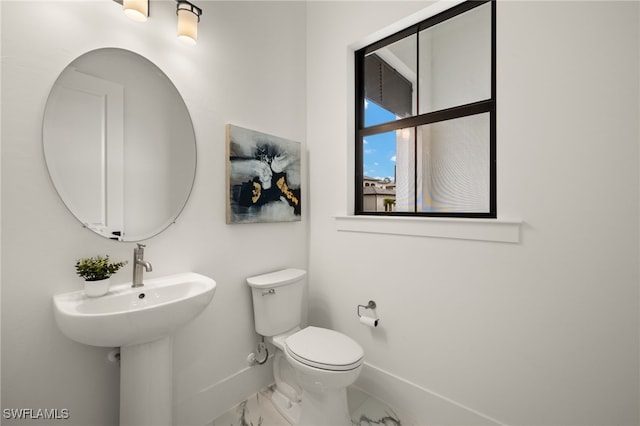 bathroom with marble finish floor, toilet, and baseboards