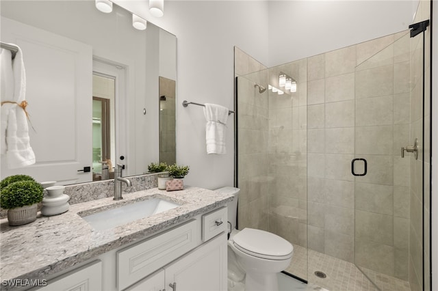 bathroom featuring toilet, a shower stall, and vanity