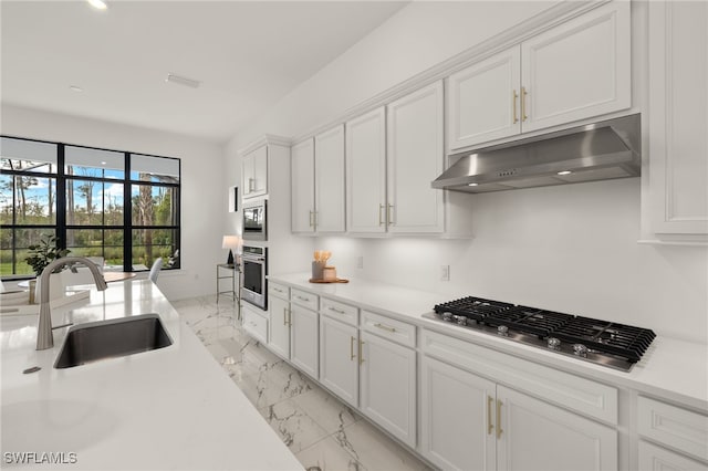 kitchen featuring light countertops, appliances with stainless steel finishes, white cabinets, a sink, and under cabinet range hood