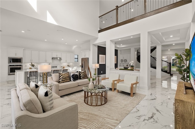 living area with recessed lighting, marble finish floor, a high ceiling, and stairs