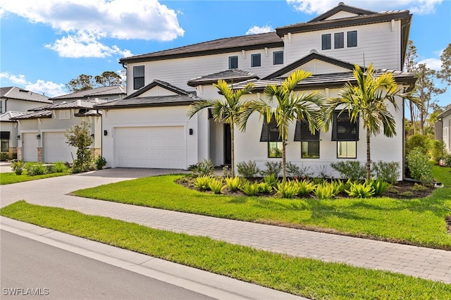 view of front facade with a garage, a front lawn, and decorative driveway