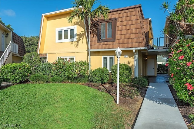 view of front of home featuring a front yard and a balcony