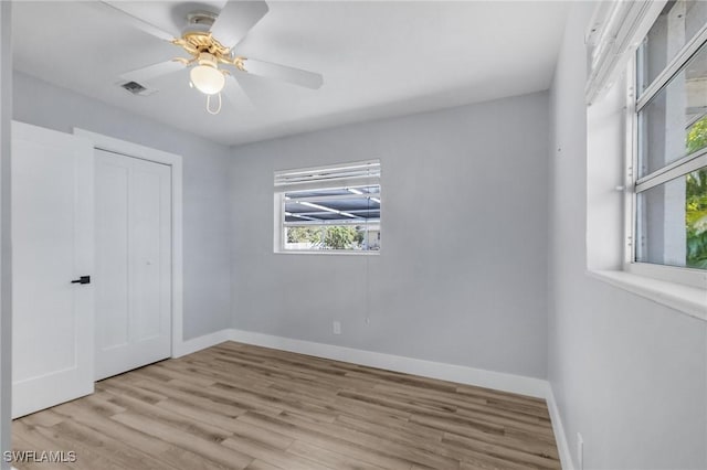 unfurnished bedroom featuring a closet, visible vents, ceiling fan, wood finished floors, and baseboards