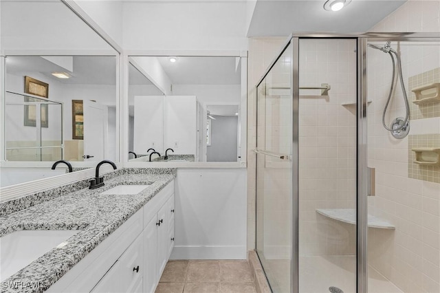 bathroom featuring double vanity, a stall shower, a sink, and tile patterned floors