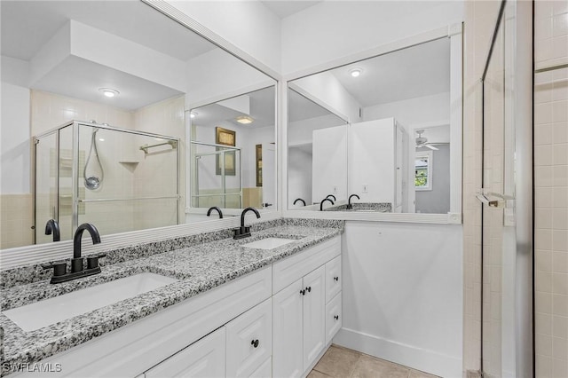 bathroom featuring double vanity, a stall shower, tile patterned flooring, and a sink