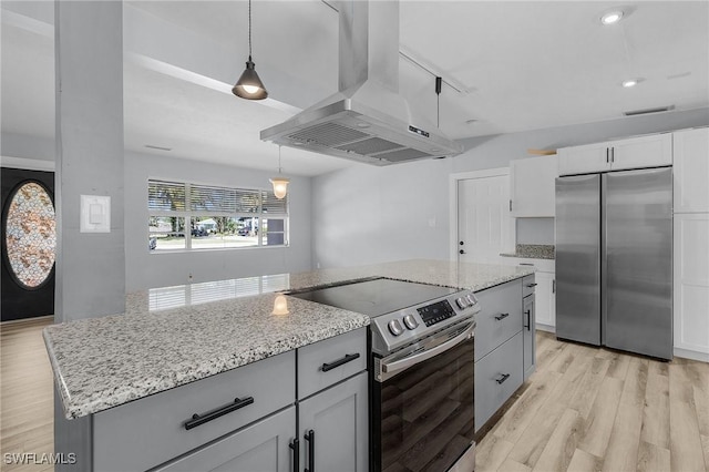 kitchen with light stone counters, extractor fan, stainless steel appliances, light wood finished floors, and an island with sink