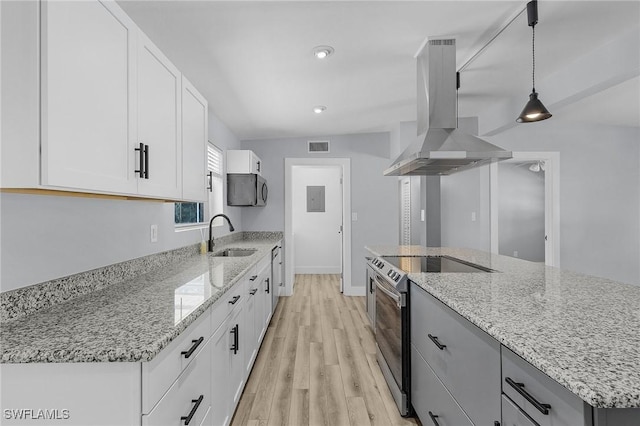 kitchen featuring light stone counters, island exhaust hood, stainless steel appliances, white cabinetry, and a sink