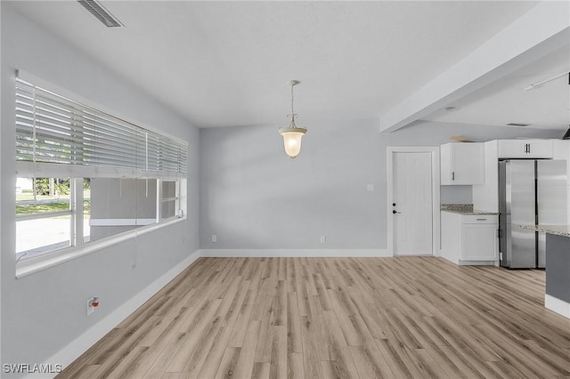 unfurnished dining area featuring visible vents, light wood-style flooring, and baseboards