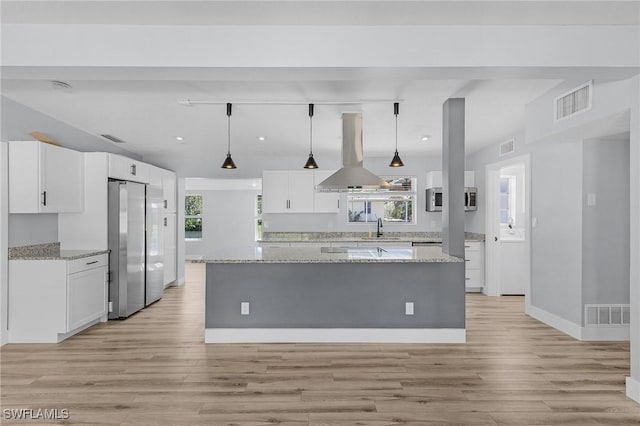 kitchen featuring island exhaust hood, white cabinetry, a sink, and freestanding refrigerator