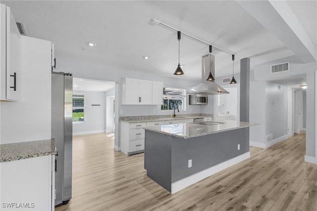 kitchen featuring a barn door, visible vents, white cabinets, stainless steel appliances, and a sink