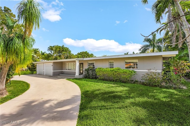 ranch-style home featuring a front yard, concrete driveway, and an attached garage