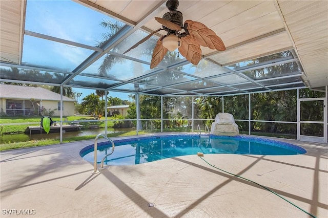 outdoor pool with glass enclosure, a patio area, and ceiling fan