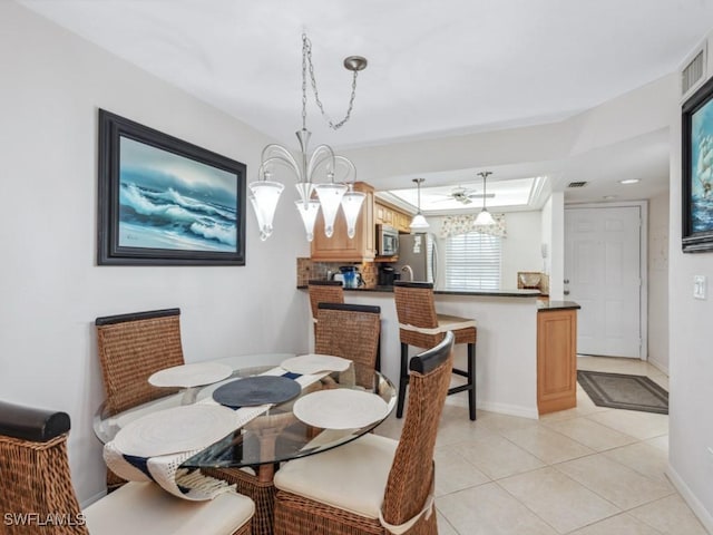 dining room featuring light tile patterned floors, baseboards, and a raised ceiling