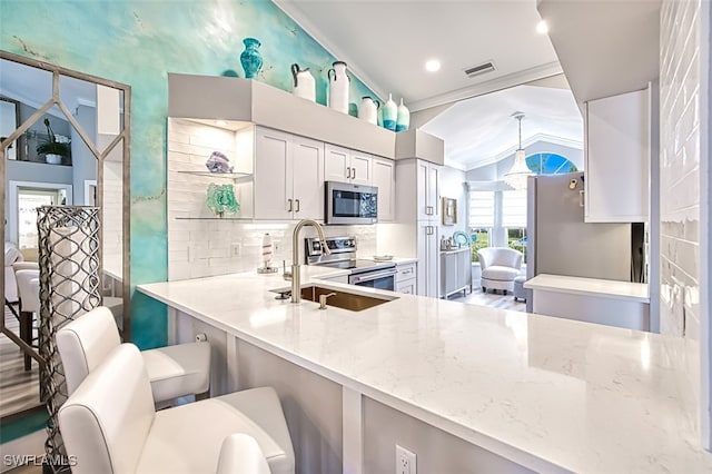 16380 Kelly Woods Dr, Fort Myers, FL 33908 - kitchen with white cabinetry, a kitchen breakfast bar, kitchen peninsula, stainless steel appliances, and light stone countertops