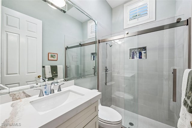 bathroom featuring vanity, a wealth of natural light, a shower with door, and toilet