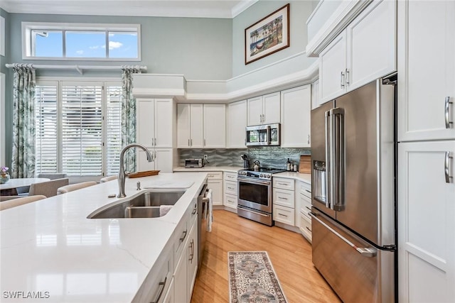 kitchen with light stone counters, sink, white cabinets, and appliances with stainless steel finishes