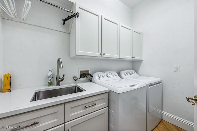 laundry room with cabinets, separate washer and dryer, sink, and light wood-type flooring