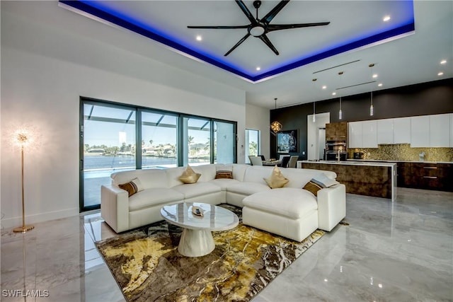 living room featuring a tray ceiling, ceiling fan, and a towering ceiling